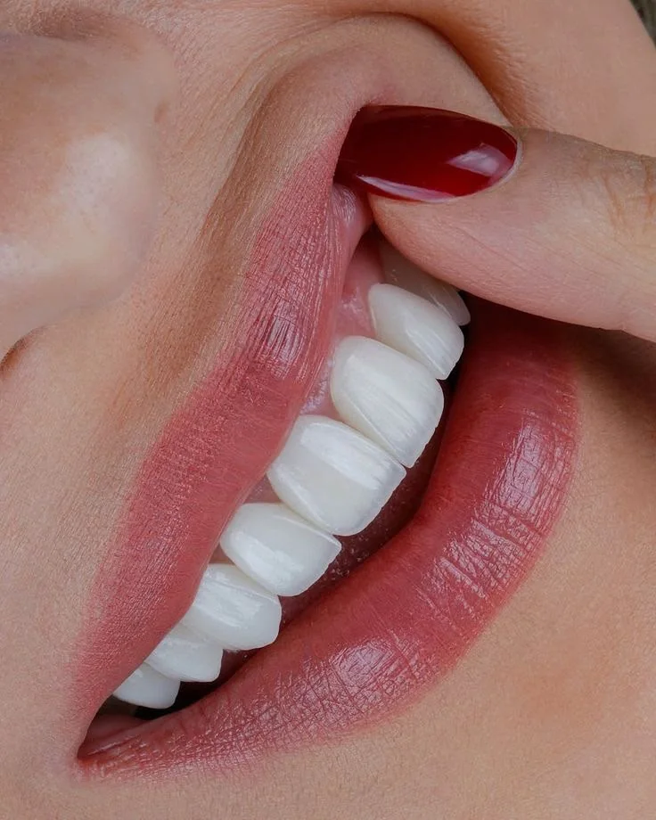 A smile with red nails touching the lip, close up